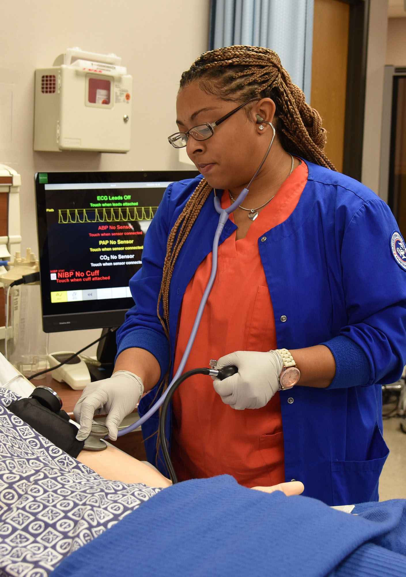 Nursing student practices taking blood pressure in a lab 