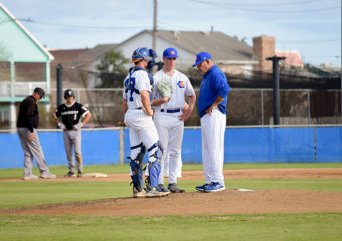 Coach and catcher go up to mound to have conversation with baseball pitcher.