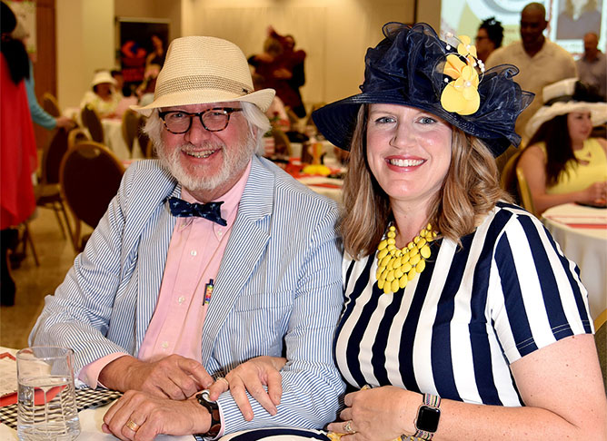 A couple dressed in Kentucky Derby attire pose for photo