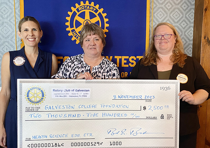 Three people pose with large donation check.