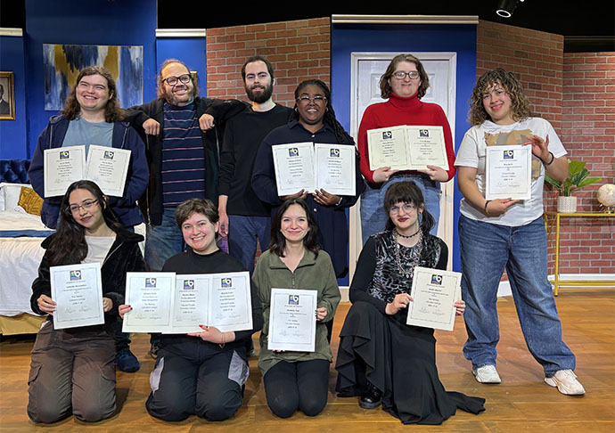 9 people stand with award certificates