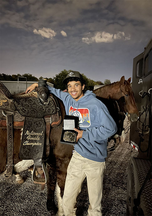Person stands next to horse displaying medal they won for a rodeo event