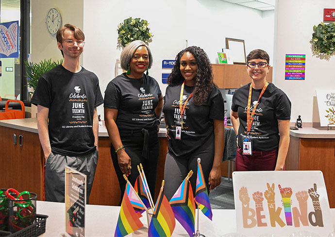 Four library staff members stand together wearing matching Juneteenth shirts