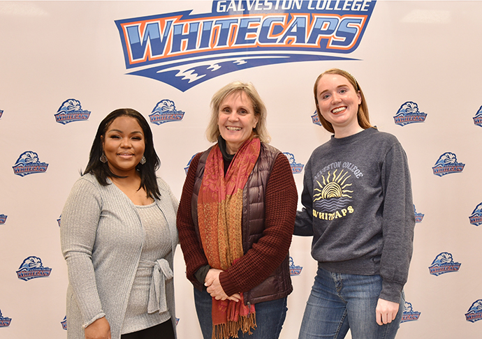 Three people pose in front of  Galveston College Whitecaps backdrop