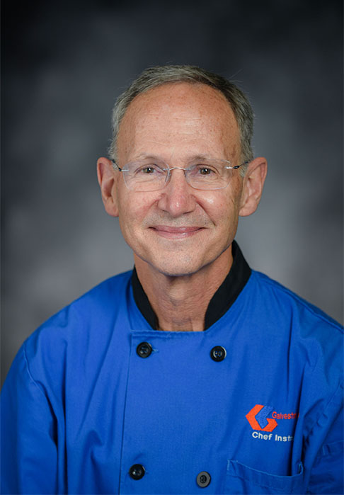 Professional portrait of person in blue chef jacket