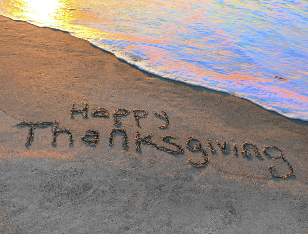 Happy Thanksgiving written in the sand on the beach